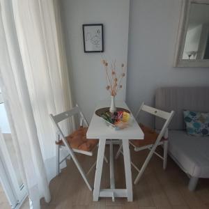 une table et des chaises blanches avec un vase. dans l'établissement Agata Azul, à Benalmádena