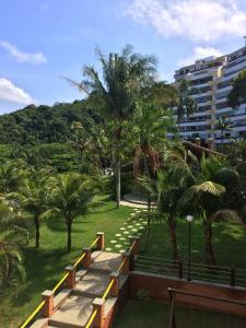 a park with benches and palm trees and a building at Sorocotuba 2 - Enseada in Guarujá