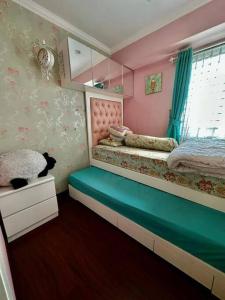 a bedroom with two beds and a cat sitting on a bench at Apartemen Green Palace View Kalibata in Jakarta