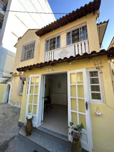 uma casa amarela com uma porta branca em Casinha Tropical no Rio de Janeiro