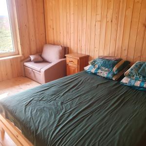 a bedroom with a bed and a chair and a window at Domek Pod Akacjami in Szypliszki