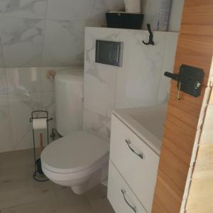 a white bathroom with a toilet and a sink at Domek Pod Akacjami in Szypliszki