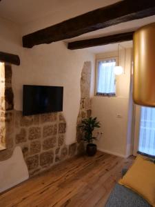 ein Wohnzimmer mit einem TV an einer Steinmauer in der Unterkunft La Bartolomea Home & Suite in Pitigliano