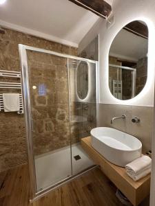 ein Bad mit einer Dusche, einem Waschbecken und einem Spiegel in der Unterkunft La Bartolomea Home & Suite in Pitigliano