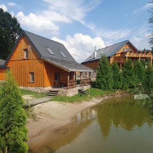 a large wooden barn with a lake in front of it at Domek Pod Akacjami in Szypliszki