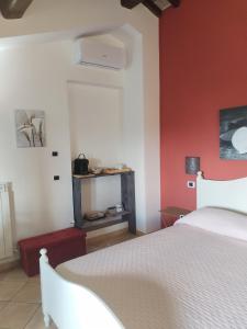 ein Schlafzimmer mit einem weißen Bett und einer roten Wand in der Unterkunft Casale Mille e una Notte in Perugia