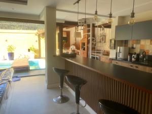 a kitchen with two bar stools and a kitchen with a pool at Loft da Beth na serra in Petrópolis