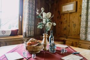una mesa con un jarrón de flores y una cesta de fruta en Nedererhof - Ferienwohnung Gamskar en Schmirn