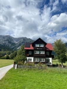 a large house with a red roof on a green field at APARTMENT DACHSTEIN - neu im Haus Wieseneck in Ramsau am Dachstein