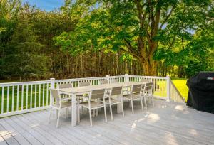 a table and chairs on a deck with a fence at Mountain Blue Vista - Luxury retreat near Ski resorts with Pond, Firepit and Hot Tub in Windham