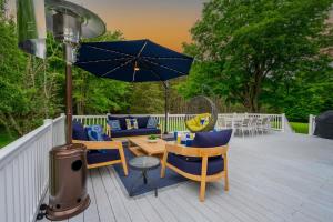 a patio with a table and chairs and an umbrella at Mountain Blue Vista - Luxury retreat near Ski resorts with Pond, Firepit and Hot Tub in Windham