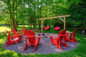 a group of red chairs and a table and a fire pit at Mountain Blue Vista - Luxury retreat near Ski resorts with Pond, Firepit and Hot Tub in Windham