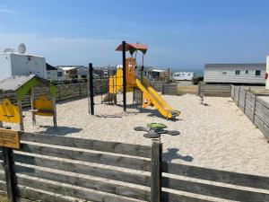 a playground with a yellow slide in the sand at Mobil-Home VUE sur MER in Le Portel