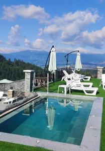 a swimming pool with white chairs and a roller coaster at Leshtenski Rai Guest House in Leshten