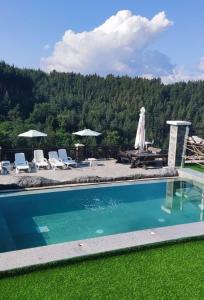 a swimming pool with chairs and umbrellas next to at Leshtenski Rai Guest House in Leshten