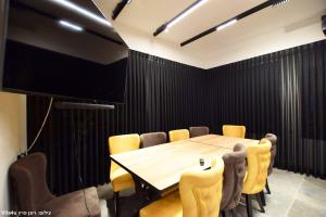 una sala conferenze con tavolo in legno e sedie gialle di אחוזת יערה a Ya‘ara