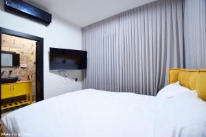 1 dormitorio con 1 cama blanca y TV de pantalla plana en אחוזת יערה, en Ya‘ara