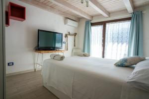 a bedroom with a large white bed and a television at Geko's House in Siracusa