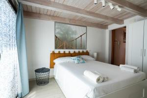 um quarto com uma cama branca e um tecto de madeira em Geko's House em Siracusa