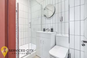 a white bathroom with a toilet and a mirror at SCA - Entertaining Studio - CR6 in Birmingham