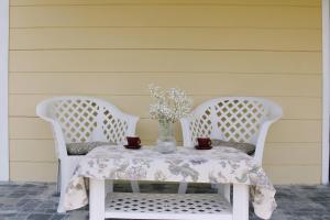 a white table with two chairs and a vase of flowers at Tiny House Kosmaj in Sopot