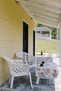 a porch with two white chairs and a table at Tiny House Kosmaj in Sopot