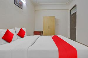 OYO Flagship Hotel Stanley Falls في جورجاون: غرفة نوم مع سرير أبيض كبير مع وسائد حمراء