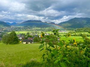 een regenboog over een groen veld met bergen op de achtergrond bij Ennstal Classic Landhaus Chalet in Irdning
