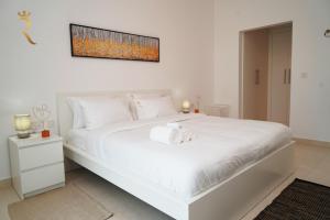 1 dormitorio blanco con 1 cama blanca grande con una foto en la pared en An Exclusive 2BR Retreat Experience Yas Island Bliss, en Abu Dabi