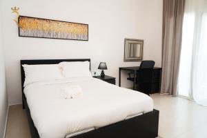 a bedroom with a large white bed and a desk at An Exclusive 2BR Retreat Experience Yas Island Bliss in Abu Dhabi