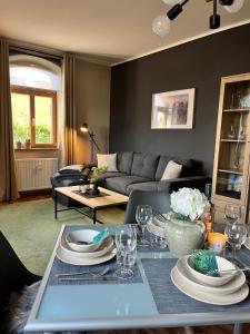 a living room with a table with plates and wine glasses at Ferienwohnung Am Bürgerteich in Bischofswerda