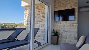 een balkon met 2 stoelen en een tv aan een bakstenen muur bij Apartments Roxsi in Novalja