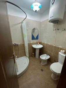 een badkamer met een toilet, een wastafel en een douche bij Cozy apartment in the City Center in Shkodër