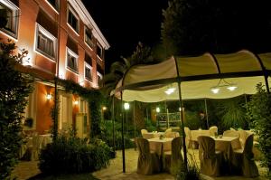 um restaurante com mesas brancas e cadeiras debaixo de um guarda-sol em Hotel Viscardo em Forte dei Marmi