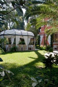 a white tent with white tables and chairs in a yard at Hotel Viscardo in Forte dei Marmi
