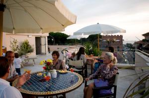 um grupo de pessoas sentadas em torno de uma mesa em um pátio em Hotel Viscardo em Forte dei Marmi