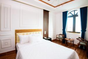 a bedroom with a large white bed with blue curtains at HÀ ANH hotel in Phường Sáu