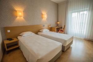 a hotel room with two beds and a window at Hotel Brazão in Vila do Conde