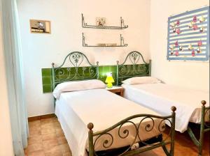 2 camas en una habitación con verde y blanco en Villa Menorquina en playa, en Cala Morell