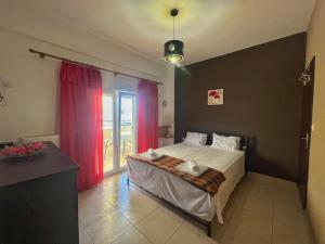 1 dormitorio con 1 cama y una ventana con cortinas rojas en Bluebay Lux Apartment of Halkidiki, en Sozopoli