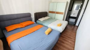 dwa łóżka z pomarańczową i niebieską pościelą w pokoju w obiekcie Mupify Homestay Jazz Suites 2 Vivacity w mieście Kuching
