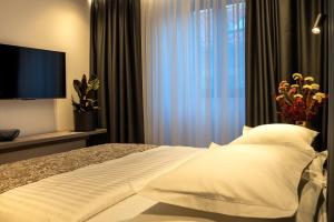 a bedroom with a bed with white pillows and a television at City Premium Heritage in Zadar