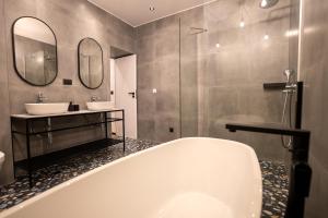 a bathroom with a tub and two sinks and a mirror at City Premium Heritage in Zadar