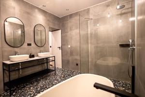 a bathroom with two sinks and a tub and mirrors at City Premium Heritage in Zadar