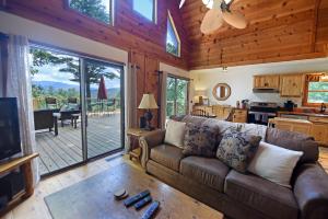 een woonkamer met een bruine bank en een keuken bij Big Pine - Long range mountain views, large decks, hot tub, fire pit and dog friendly! in Blairsville