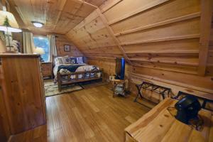 Dormitorio con cabaña de madera, cama y TV en Big Pine - Long range mountain views, large decks, hot tub, fire pit and dog friendly!, en Blairsville