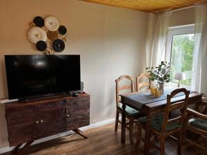 uma sala de estar com uma mesa e uma televisão num armário de madeira em Fewo Plüschmors em Dornum