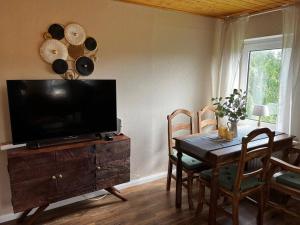 a living room with a table and a television on a wooden cabinet at Fewo Plüschmors in Dornum