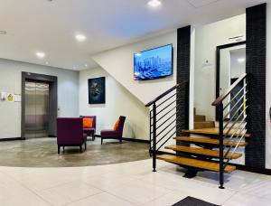 a lobby with stairs and chairs and a tv on the wall at Kino Hotel in Shah Alam