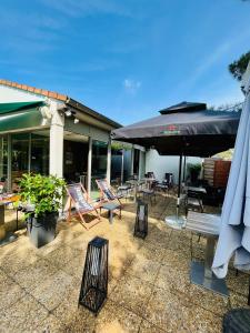 un patio con un montón de sillas y sombrillas en Campanile Toulouse Nord l'Union en LʼUnion